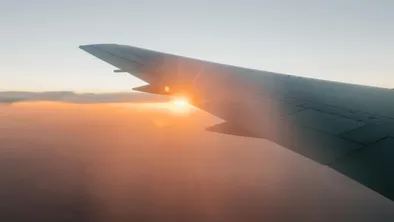 Закат в облаках под крылом летящего самолета