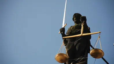 Фемида с весами и мечом на крыше здания на фоне голубого неба