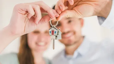 Счастливые мужчина и женщина держат ключ от квартиры