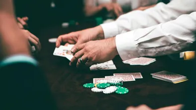 Руки крупье, раздающего карты за игральным столом в казино