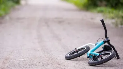 Детский двухколесный велосипед лежит на лесной дороге