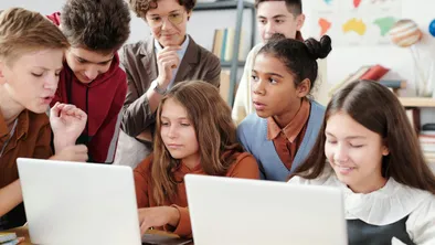 Увлеченные школьники смотрят в ноутбуки под присмотром учительницы