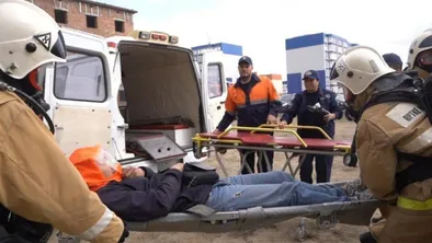 Спасатели несут пострадавшего на носилках в машину во время учений