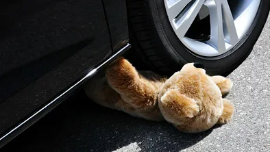 плюшевый мишка под колесом автомобиля