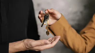 Женщина передает ключи от квартиры мужчине